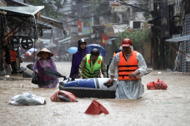 People push an inflatable boat through the flood waters in a street of Hanoi, Vietnam, Wednesday in the aftermath of Typhoon Yagi that brought heavy rain and flooded northern Vietnam (EPA-Yonhap)