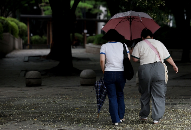 Pedestrians walk through the rain in Jongno, Seoul, Sunday. (Yonhap)