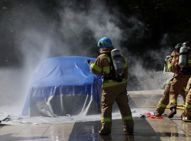 Firefighters extinguish an electric vehicle fire during a drill at an apartment complex in Seoul on Aug. 28, following a recent series of similar incidents. (Yonhap)