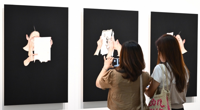 Visitors observe paintings by Lee Jin-ju at the Arario Gallery's booth at Frieze Seoul 2024, during a VIP opening Wednesday at Coex in southern Seoul. (Im Se-jun/The Korea Herald)