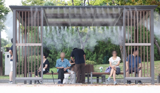 Visitors of Yeouido Park in Yeongdeungpo-gu, western Seoul, sit under a cooling fog as daytime temperatures reached as high as 34 degrees Celsius on Wednesday. (Yonhap)